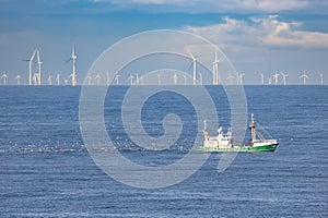 A cutter on the North sea with wind turbines in the background