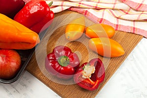 Cutting board with assort of different tomatoes and bell pepper on white wooden background