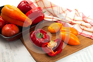 Cutting board with assort of different tomatoes and bell pepper on white wooden background