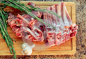 cutting board with fresh lamb ribs decorated with rosemary and g