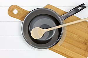 Cutting board with frying pan and wooden spoon