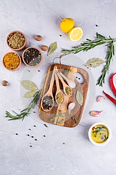 Cutting board with herbs and spices - rosemary, garlic, salt, pepper, olive oil, lemon. Culinary background.