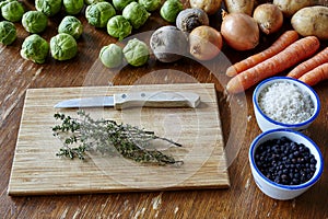 Cutting board with herbs surrounded by vegetables