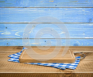 Cutting board, kitchen towel on blue wooden background, side view