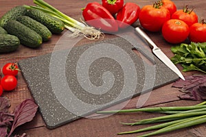 Cutting board, knife, vegetables greens for making salad on wooden table
