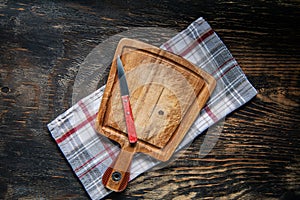 Cutting board over towel on dark wooden kitchen table. Top view