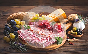 Cutting board with prosciutto, salami, ham, cheese, bread and olives