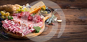 Cutting board with prosciutto, salami, ham, cheese, bread and olives