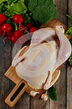 On cutting board, raw chicken is ready for cooking.