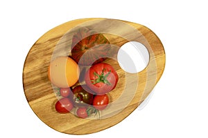 Cutting board in shape of an artist palette with multi-colored tomatoes on it; top view.