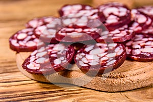 Cutting board with sliced salami sausage on a wooden table