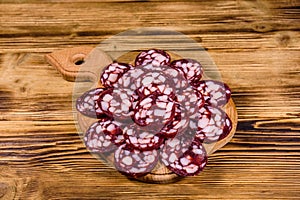 Cutting board with sliced salami sausage on a wooden table