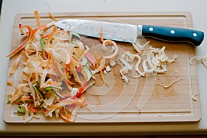 cutting board with vegetable peelings and a used knife