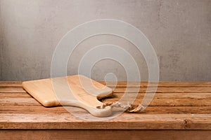 Cutting board on wooden deck table over rustic wall background. Cooking