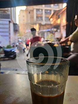 Cutting chai glass of hot tea kept on restraunt table in Bandra Mumbai in foreground