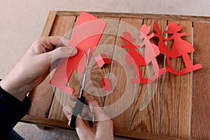 Cutting a chain of red paper dolls with scissors