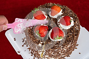 cutting chocolate birthday cake with strawberries