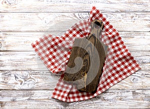 Cutting chopping brown wooden board decorated with red picnic checkered cloth top view. Empty timber,plank. Dish plate