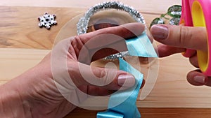 Cutting ends of handmade blue bow made from silk ribbon and burning with lighter.Christmas DIY. Winter ornaments decor