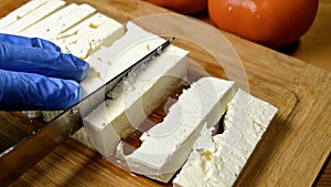 cutting feta cheese on wooden board