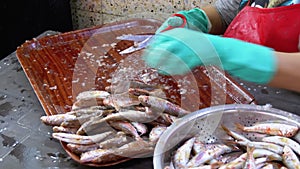 Cutting fish in market stall. Woman manual cleaning and cuts fresh fish
