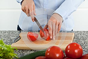 Cutting fresh red tomatoes on cutting board