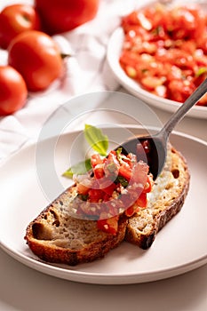 Cutting fresh tomato and preparng homemade bruschetta with olive oil, garlic and basil