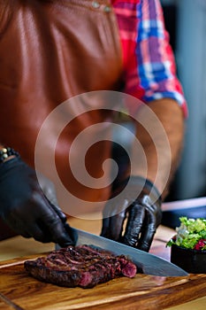 Cutting freshly cooked beef steak on a wooden board