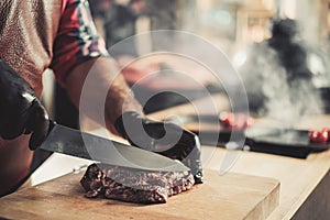 Cutting freshly cooked beef steak on a wooden board