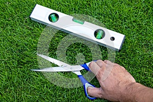 Cutting the grass with scissors and using the level tool to level the lawn