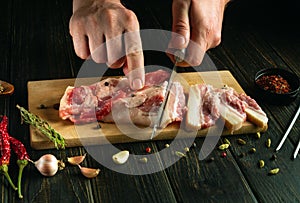 Cutting lard with a knife on a kitchen board. Low key concept of cooking lard with spices on the kitchen table