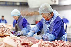 Cutting meat in slaughterhouse. The meat and sausage factory.