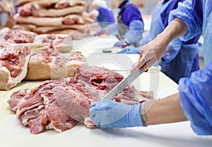 Cutting meat in slaughterhouse. The meat and sausage factory.