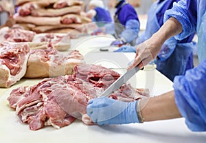 Cutting meat in slaughterhouse. The meat and sausage factory. photo