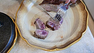 Cutting medium rare beef steak on a plate. Juicy meat