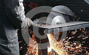 Cutting of metal. Closeup men`s hands cutting metal with a circular saw. Sparks fly to the side.