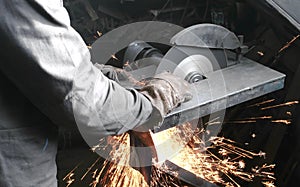 Cutting of metal. Closeup men`s hands cutting metal with a circular saw. Sparks fly to the side.