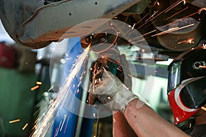 Cutting metal part with sparks in car service station close up.