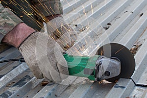 Cutting metal sheet with a special electric tool. Sparks fly. Self-repair of the roof, corrugated iron roof. Close-up photo