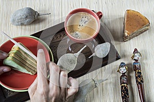 Cutting multi-layered cake called lapis legit or spekkoek, with bamboo napkin and Indonesian souvenir