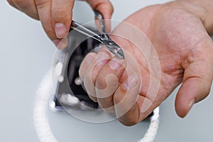 Cutting the nail with professional manicure scissors. A man gives himself a manicure