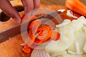 Cutting onion carrot on board with knife,  bunch