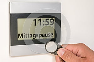 Cutting out the lunch break at a time clock with the word lunch break in german language