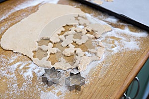 Cutting out star shaped cinnamon Christmas cookies with biscuit