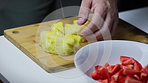 cutting pineapple on a board with a knife