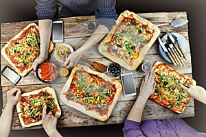 Cutting pizza. Domestic food and homemade pizza. Enjoying dinner with friends. Top view of group of people having dinner together