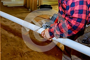 Cutting plastic pipe by special red scissors. Close up of male hands working with pipe