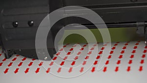 Cutting plotter machine making small round red arrows stickers, closeup detail
