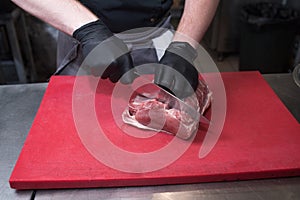 Cutting pork meat. Chef working in the kitchen in a pub.