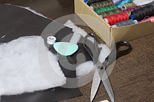 Cutting of the product for sewing. On the table is a cloth with chalk-marked garments. Nearby lie scissors, chalk and a box with c